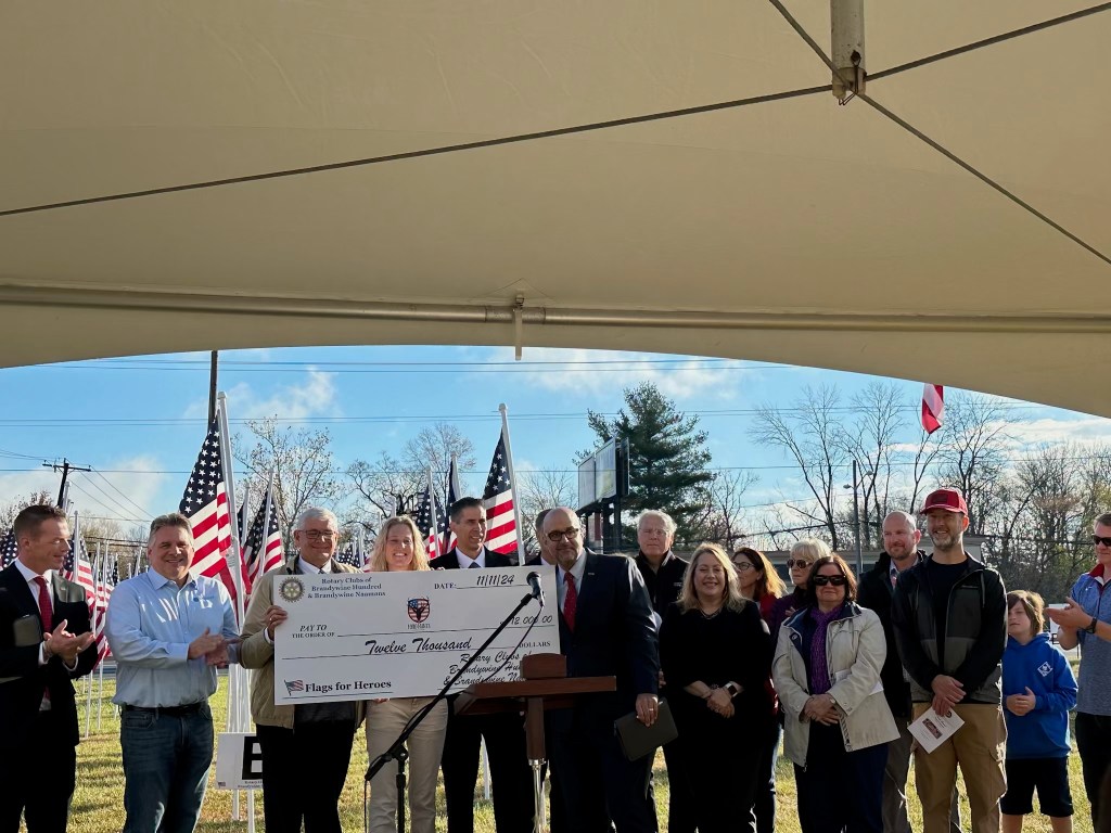 The Hero Hunts Foundation team and representatives from the Rotary Clubs pose with a large check representing a $12,000 donation.